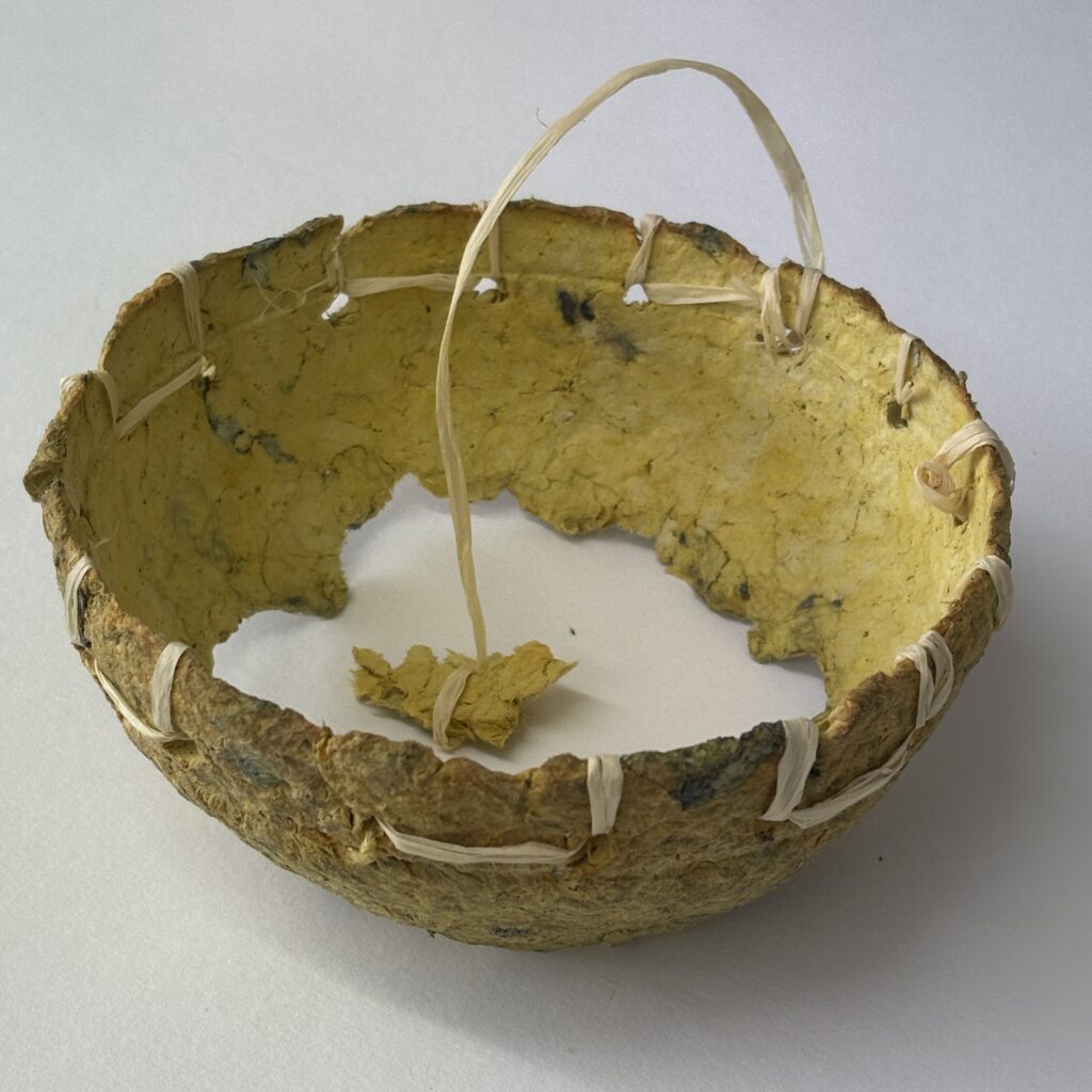 Yellow paper maché bowl with yellow amulet.