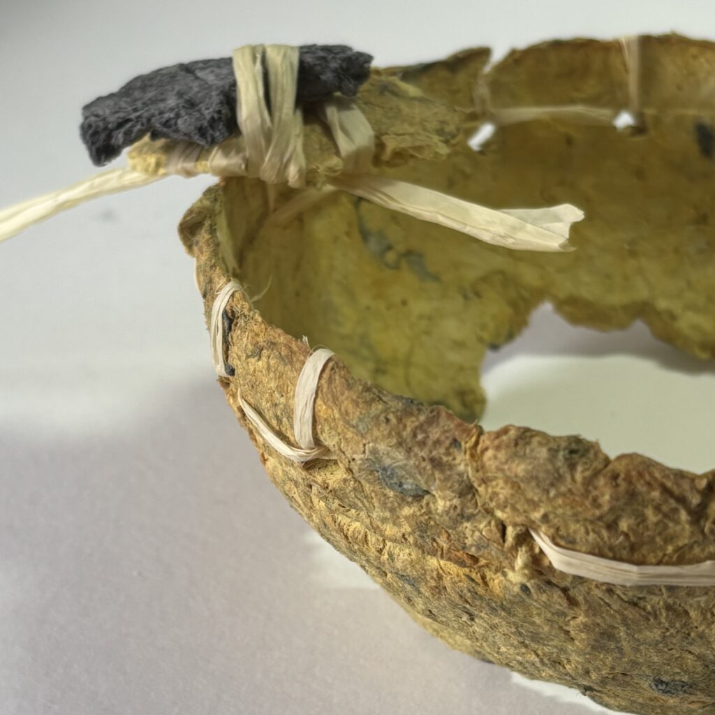 Yellow paper maché bowl with black amulet.