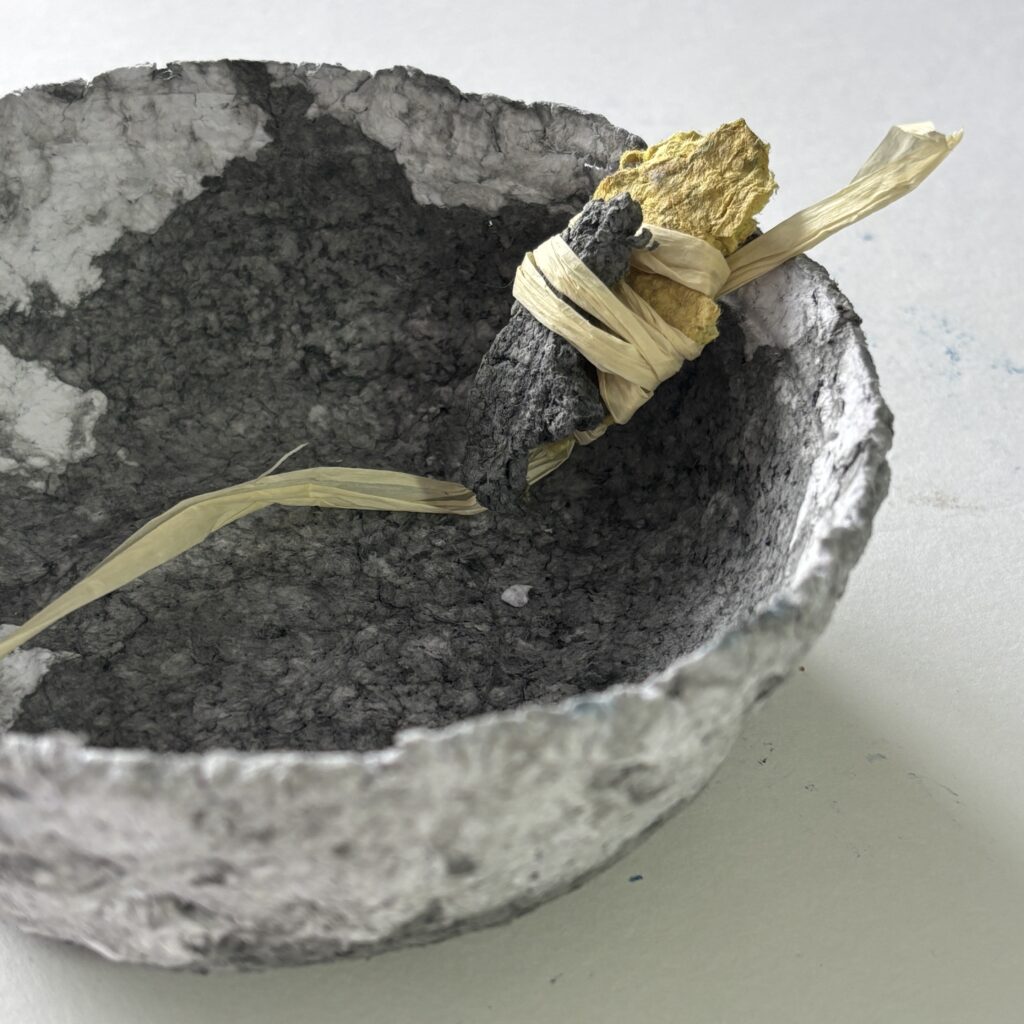 Black paper maché bowl with raffia and amulet