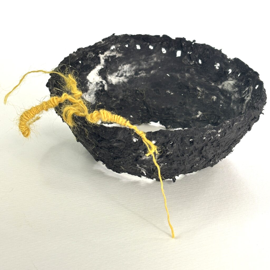 Black paper maché bowl with yellow thread.